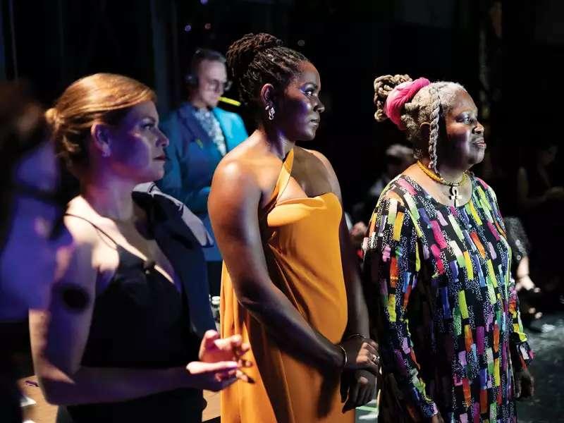 Olivia watkins looking to the left standing on a stage with other women